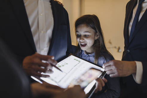 Business people and girl looking at shining construction plan on tablet in office - GUSF02722