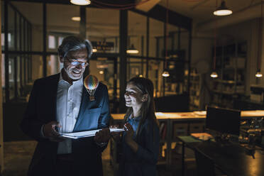 Happy senior buisinessman and girl with hot-air balloon and shining tablet in office - GUSF02725