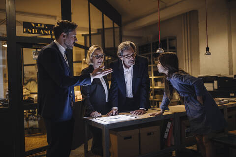 Geschäftsleute diskutieren mit Mädchen und leuchtendem Tablet im Büro, lizenzfreies Stockfoto