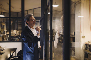 Senior businessman drawing on glass pane in office - GUSF02739