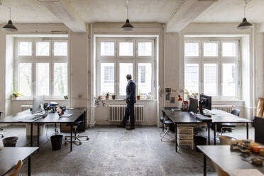 Älterer Geschäftsmann im Büro mit Blick aus dem Fenster - GUSF02765