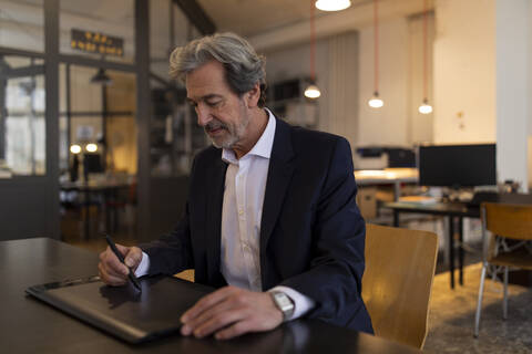 Senior businessman using graphics tablet at desk in office stock photo