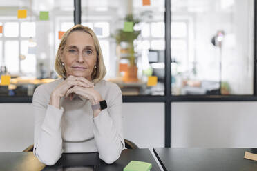 Portrait of confident mature businesswoman sitting at desk in office - GUSF02797