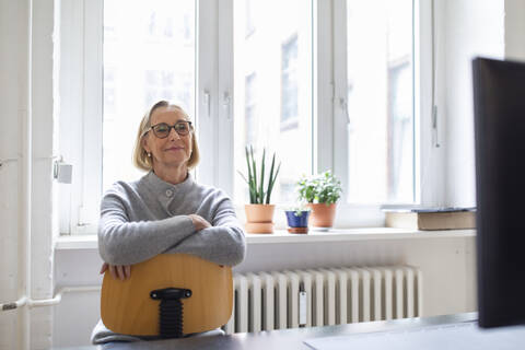 Mature businesswoman sitting on chair in office stock photo