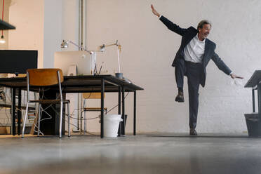 Happy senior businessman doing gymnastics in office - GUSF02809