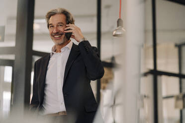 Smiling senior businessman on the phone in office - GUSF02822