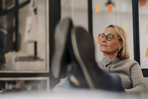 Mature businesswoman in office with feet on desk stock photo