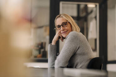 Portrait of mature businesswoman sitting at desk in office - GUSF02830