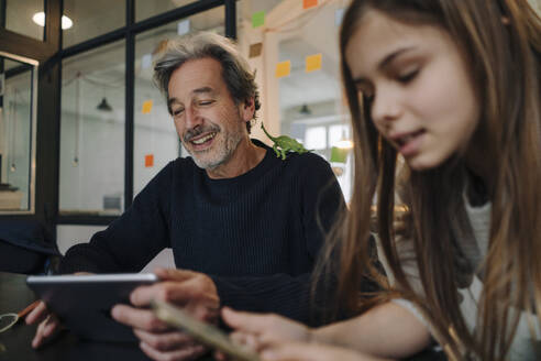 Casual senior buisinessman and girl using tablet and smartphone in office - GUSF02865