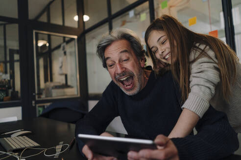 Happy casual senior buisinessman and girl using tablet in office - GUSF02868