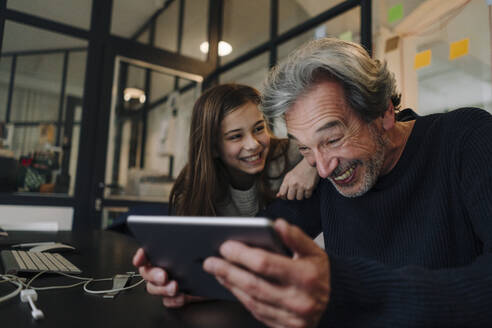 Happy casual senior buisinessman and girl using tablet in office - GUSF02871