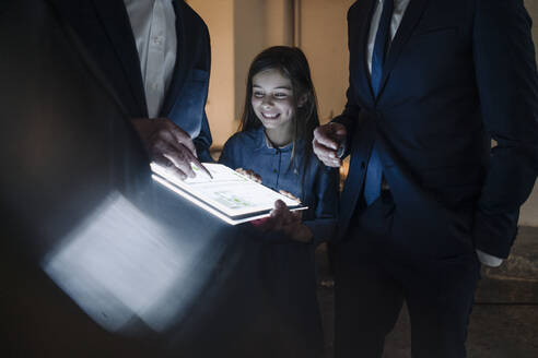 Business people and happy girl looking at shining construction plan on tablet in office - GUSF02882