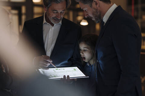 Business people and girl looking at shining tablet in office stock photo