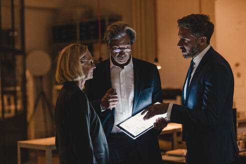 Geschäftsleute mit leuchtendem Tablet im Gespräch im Büro - GUSF02893