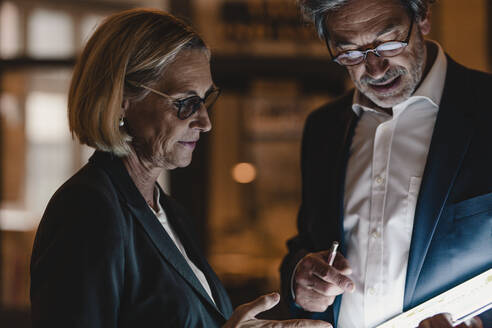 Businessman and businesswoman with tablet talking in office - GUSF02895