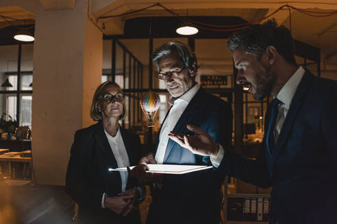 Geschäftsleute mit leuchtendem Tablet und schwebendem Heißluftballon im Büro - GUSF02897