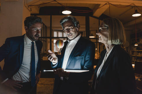 Geschäftsleute mit leuchtendem Tablet und schwebendem Heißluftballon im Büro - GUSF02898