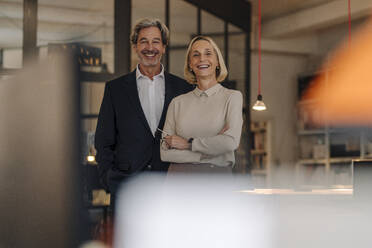 Portait of smiling businessman and businesswoman in office - GUSF02902