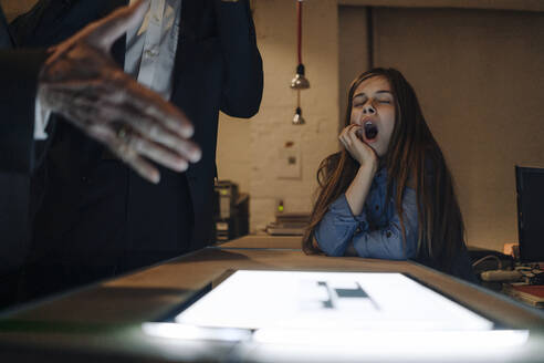 Businessman and yawning girl with shining tablet in office - GUSF02915