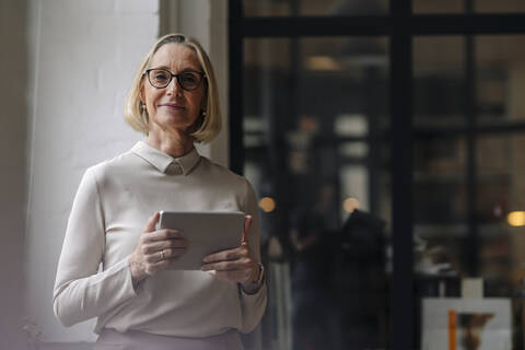 Porträt einer reifen Geschäftsfrau, die ein Tablet im Büro hält, lizenzfreies Stockfoto