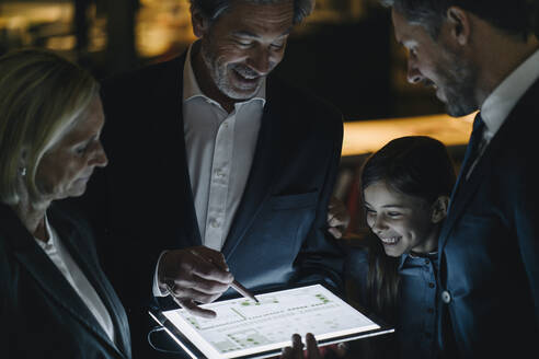 Business people and girl looking at shining tablet in office - GUSF02945