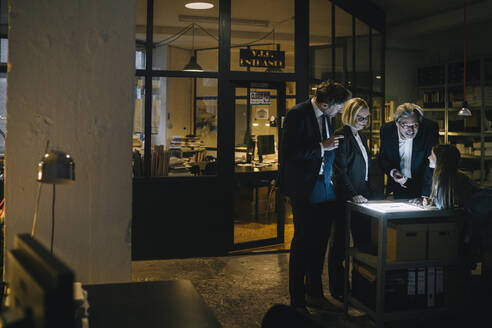Geschäftsleute und Mädchen schauen auf leuchtende Tablet im Büro - GUSF02949