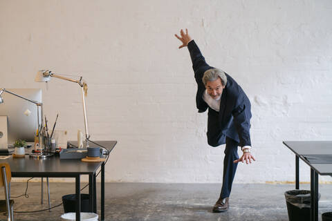 Älterer Geschäftsmann macht Gymnastik im Büro, lizenzfreies Stockfoto