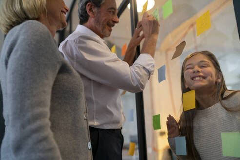 Businessman and businesswoman with mischievous girl in office - GUSF02962