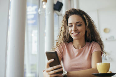 Young student looking on her smart phone at the coffee shop - MOMF00809