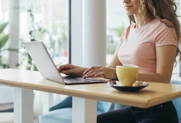 Junge Studentin bei der Arbeit an ihrem Laptop in einem Café - MOMF00814