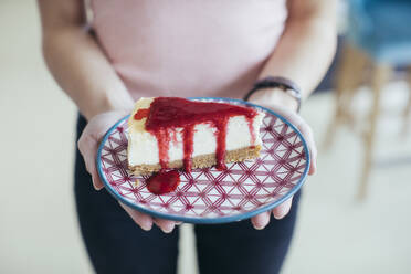 Frau hält einen Teller mit roh-veganem Kuchen - MOMF00826