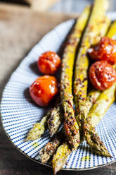 Gegrillter grüner Spargel mit Kirschtomaten auf einem Teller - SBDF04130