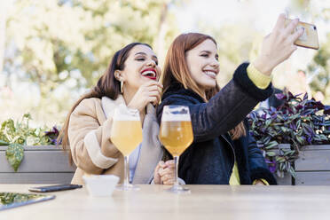 Zwei Freundinnen machen ein Selfie im Freien in einem Café - ERRF02203