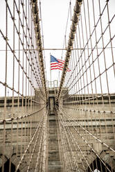 USA, New York, New York City, Cables of Brooklyn Bridge with American flag standing on top - CJMF00177