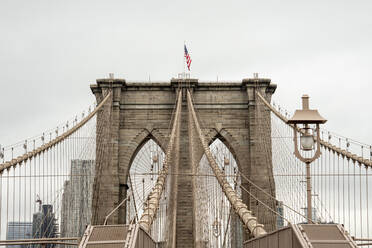 USA, New York, New York City, Cables of Brooklyn Bridge with American flag standing on top - CJMF00179