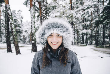 Portrait of happy young woman in winter forest - OCMF00929