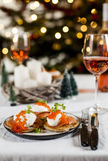 Blinis mit Sauerrahm, Räucherlachs und Fischrogen, vor der Weihnachtsdekoration - SBDF04139