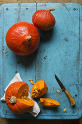 Rote Kurikürbisse (Cucurbita maxima) auf blauem Schneidebrett - ASF06539