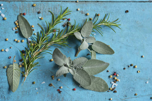 Rosemary, sage, salt and pepper lying on blue cutting board - ASF06546