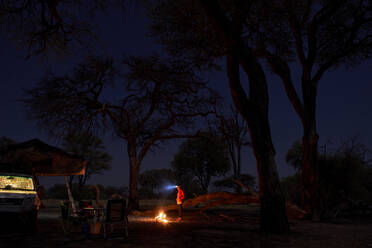 Frau auf einem Campingplatz bei Nacht am Lagerfeuer, Khwai, Botswana - VEGF00859