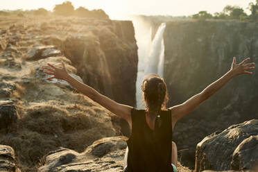 Woman with arms open enjoying the view to Victoria Falls, Zimbabwe - VEGF00860