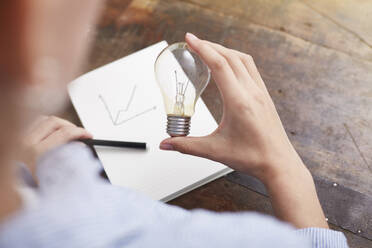 Woman with electric bulb planning way to save energy and money - ISF22971