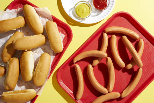 Tablett mit Fingerbrötchen und Tablett mit Hotdogs auf gelbem Hintergrund - ISF23062