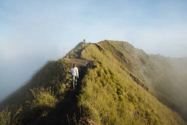 Junge Touristin beim Wandern auf dem Gipfel eines nebligen Berges, Rückansicht, Bali, Indonesien - ISF23073