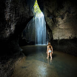 Junge Touristin im Bikini mit Blick auf Felsformation Wasserfall, Rückansicht, Bali, Indonesien - ISF23080