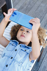 Kleines Mädchen benutzt Smartphone auf Bank - ISF23105