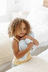 Little girl cuddling soft toy in bedroom - ISF23135