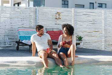 Couple enjoying iced drink by swimming pool - ISF23142