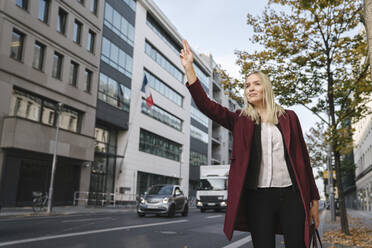 Blonde Geschäftsfrau in der Stadt, die ein Taxi ruft - AHSF01356