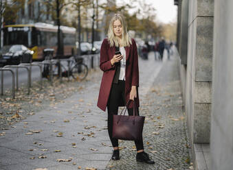 Blond businesswoman using smartphone in the city - AHSF01392